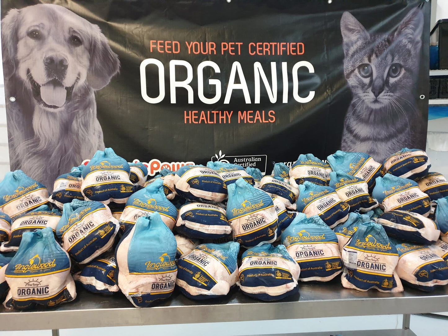 Packs of organic chicken with a banner featuring a dog and cat in the background.