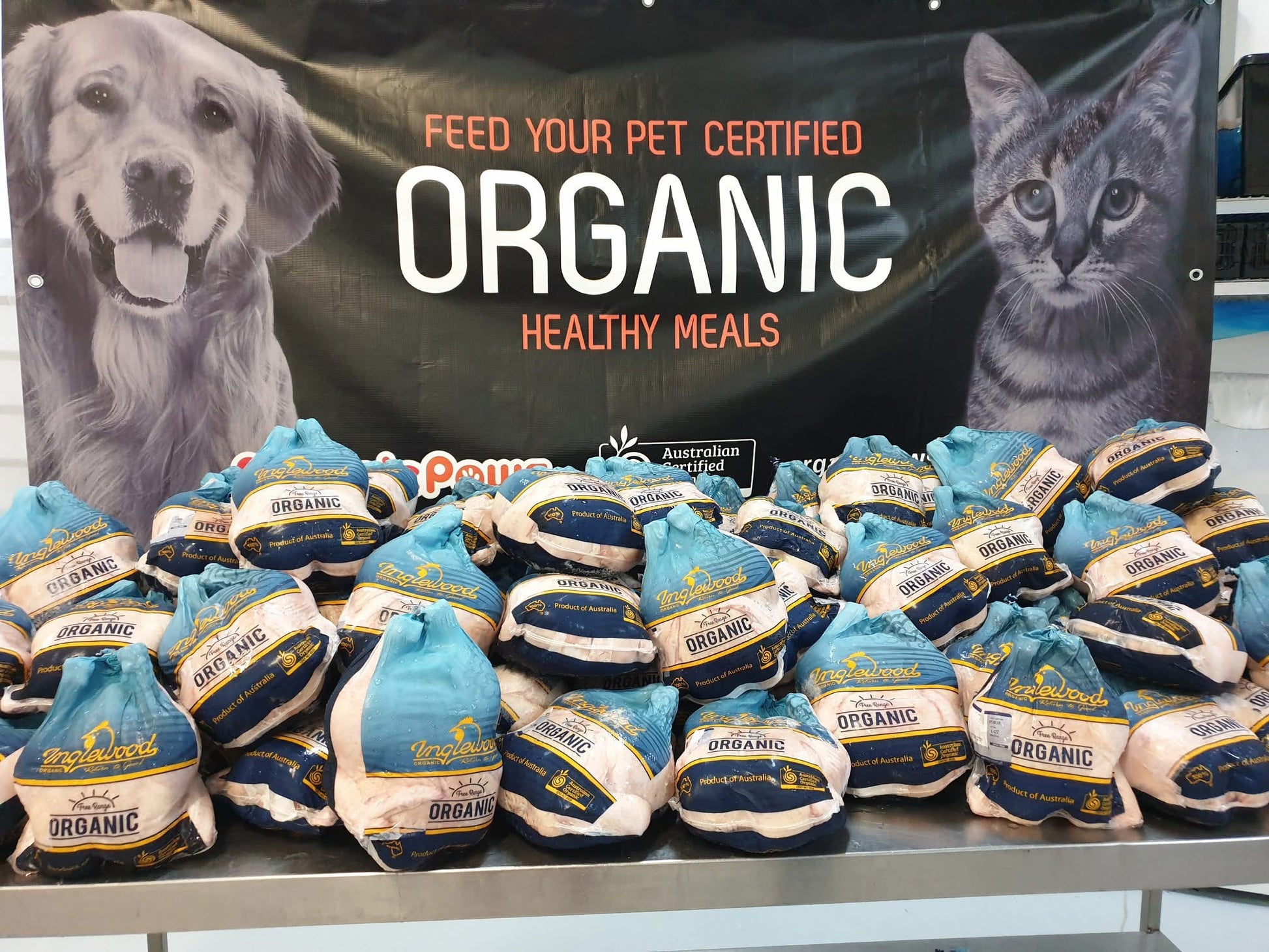 Packs of organic chicken with a banner featuring a dog and cat in the background.