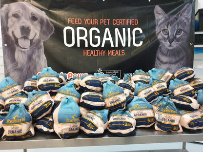 Packs of organic chicken with a banner featuring a dog and cat in the background.