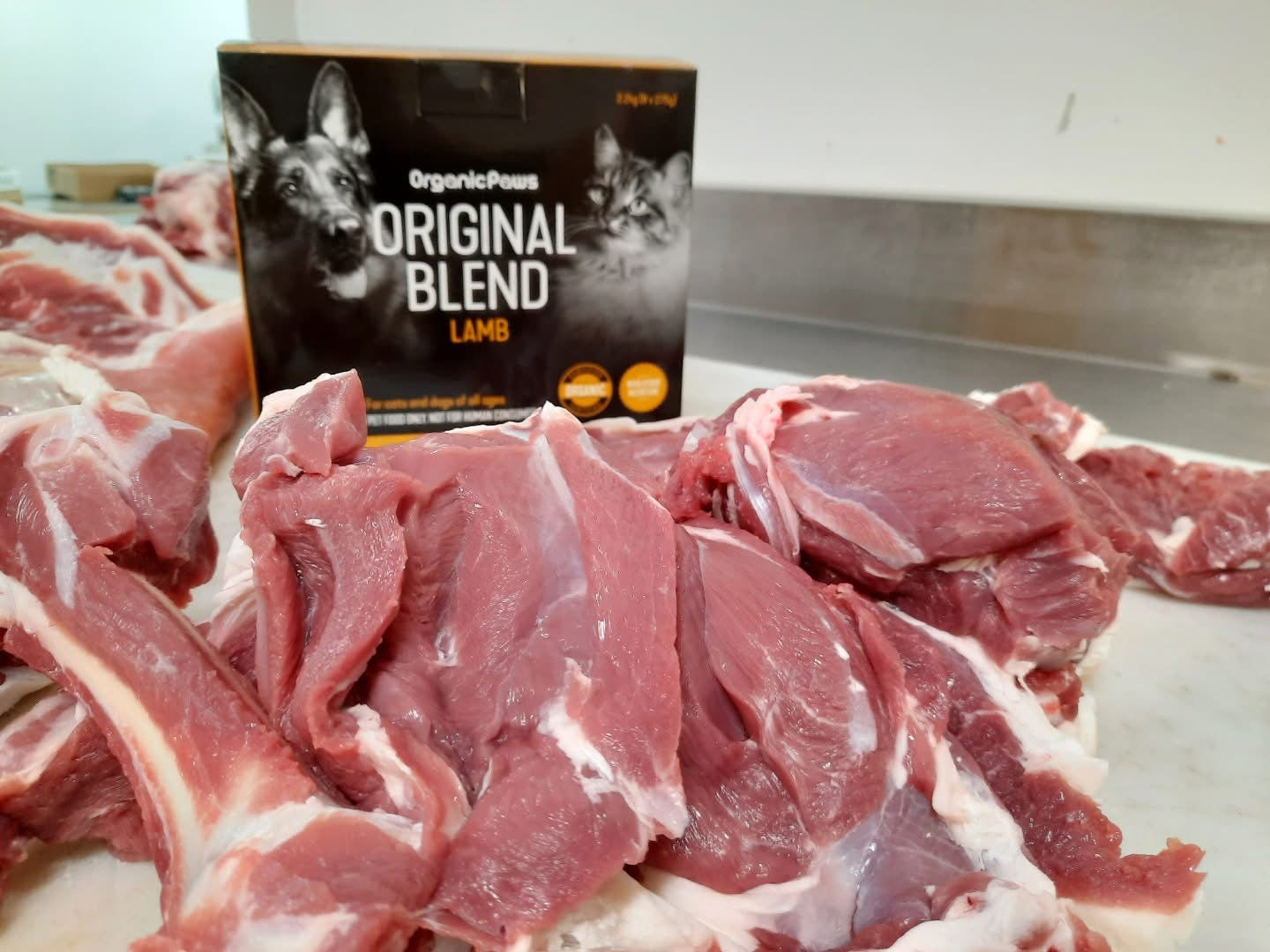 Raw lamb meat with Organic Paws Original Blend Lamb packaging on a table.