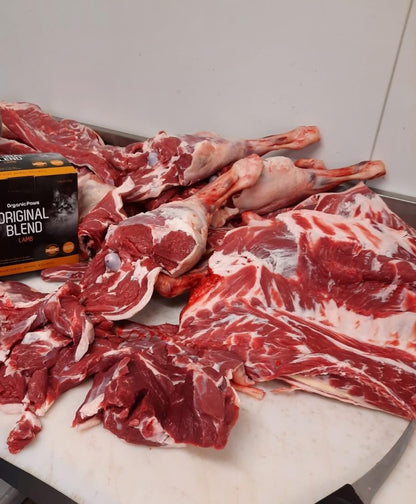 Raw meat on a cutting board with a box of Original Blend dog food in the background.